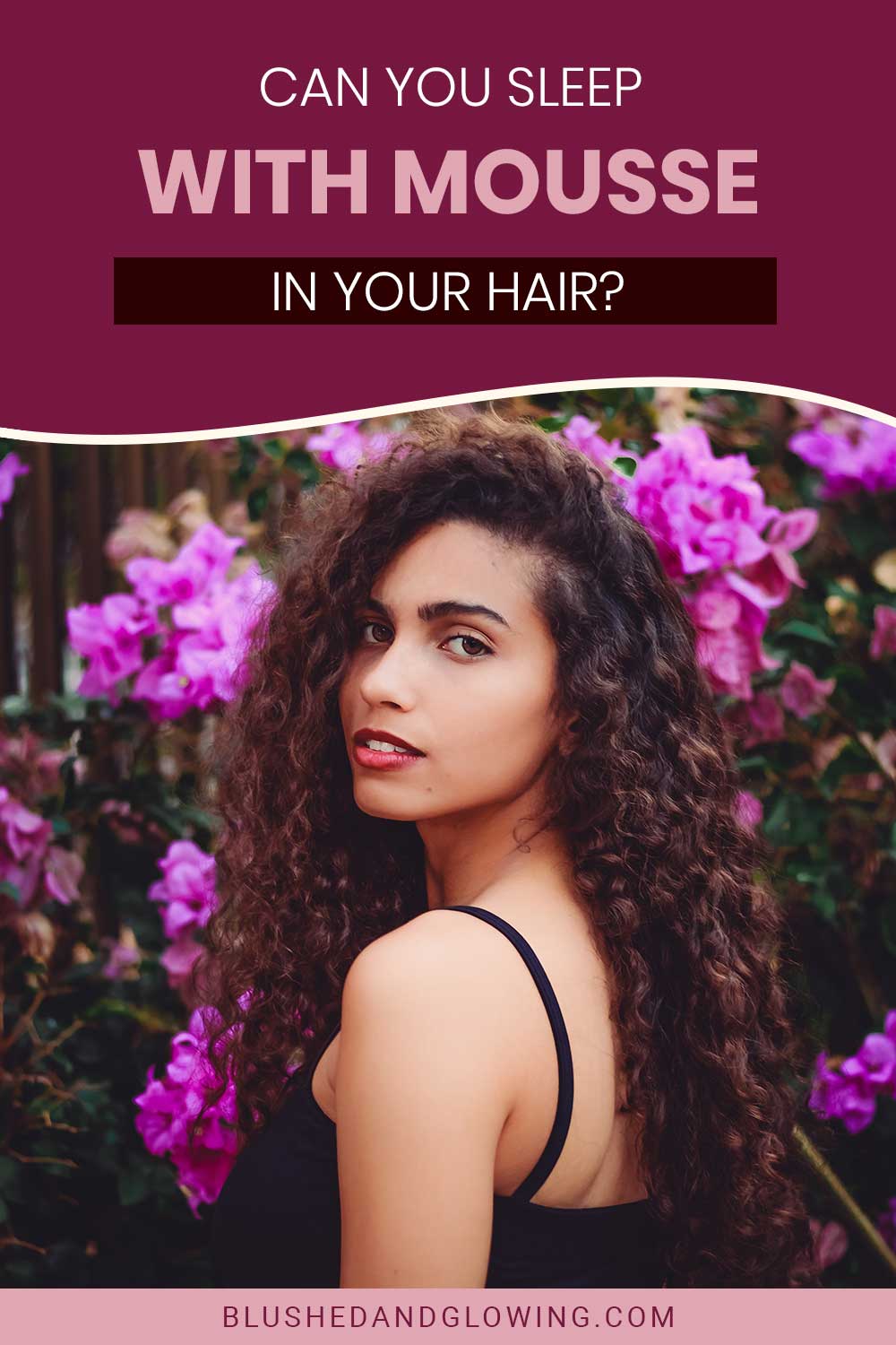 Woman with curly hair in front of a flower tree - Can You Sleep With Mousse In Your Hair?